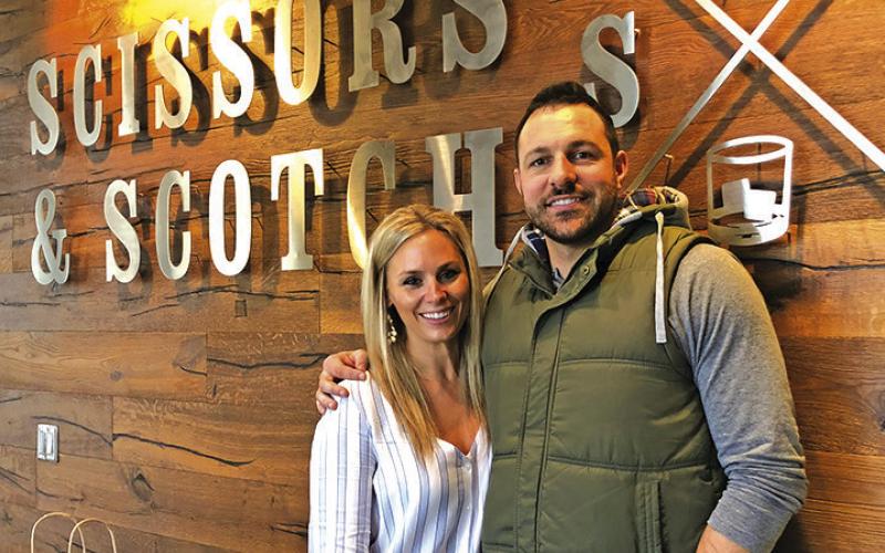 Courtesy Photo Tanner Wiles, along with his Director of Grooming Brandi Busboom, take a photo in front of the Scissors &amp;amp; Scotch signage at his Lincoln location.