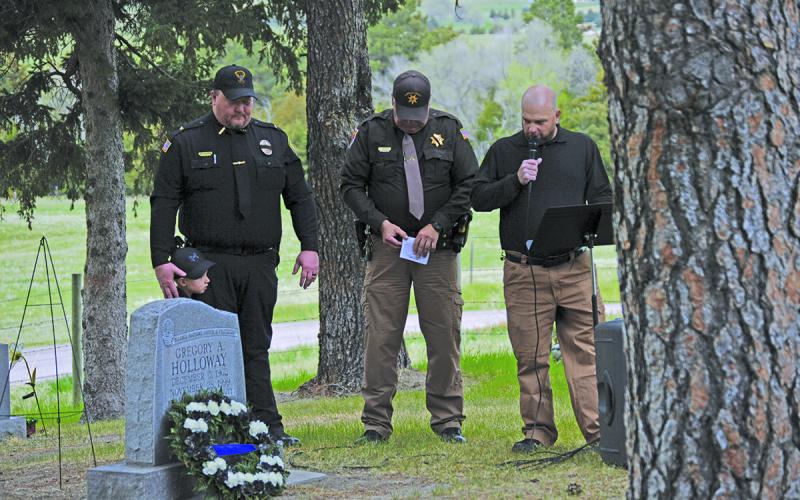 (Photo by Courtney Ostrander) Gordon Police Chief Clay Heath, Sheridan County Sheriff Jeff Brewer, and Jason Gantz bow their heads in prayer at the Gordon Cemetery in honor of Police Memorial Week.