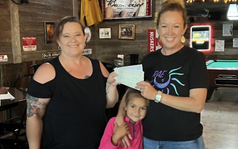 (Courtesy Photo) Smitty’s Place owner Misty Belsky (left) presents a check to Julie and Sloane Linders in benefit of the organization McKenna’s Rae of Hope.