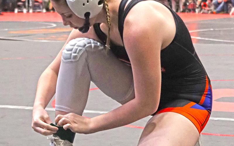 (Photo by Scott Bidroski) Senior Kirsten Heck puts on her green ankle band prior to her match on Saturday, January 24 in which she would win her 100th career match as a Mustang wrestler.