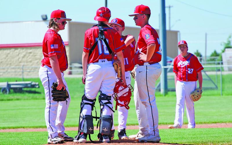 (Photo by Richae Malara) The Regulator Prep team has a meeting on the mound prior to the start of an inning against Sidney on Sunday, June 1. The Prep team lost both games to the Raiders but kept things close in both contests at Historic Modisett Ball Park.