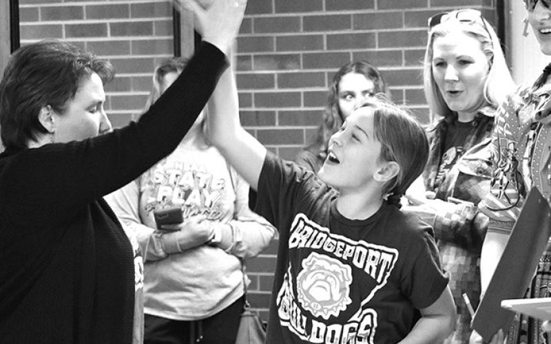Photo by Chabella Guzman Completing her round with a high score, Brynn Little, center, of Bridgeport, gets a high-five from a fan.