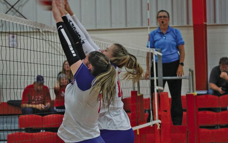 (Photo by Michele Heck) Seniors Kirsten Heck and Taleigh Starr block the kill attempt from the Kimball Longhorns. Heck, Starr, and the Mustangs finished their day with a 1-1 record to start the season.
