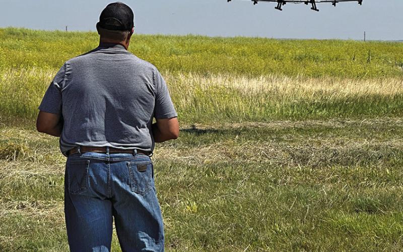 Photo by Heidi Beguin Southpaw Aerial Co., LLC’s Seth Tausan helps guide the spray drone as it comes in for a landing.