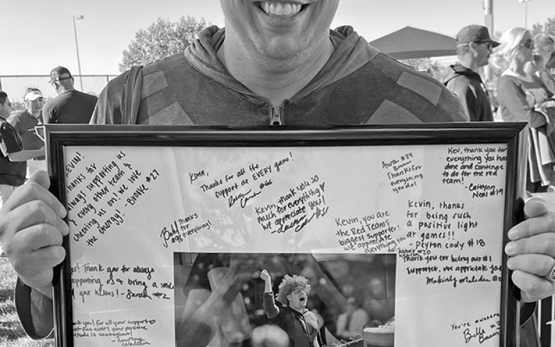 Courtesy Photo Kevin Coleman, dressed as Super Fan, holds a signed photo from the Husker softball team thanking him for being their biggest supporter. “These players are his people and they know it and that’s why they love him,” said Jon Squier, whose daughter Abbie plays on the team.