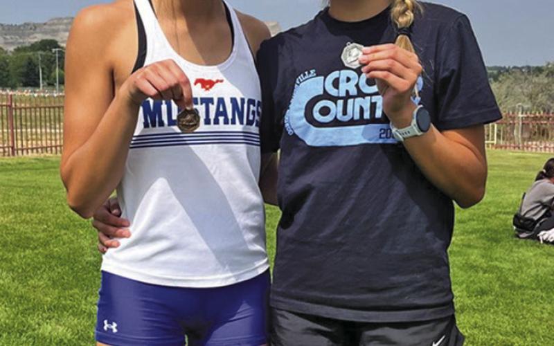 (Photo by Amy Schmidt) Brittney Dehning (left) and Rarity Cournoyer (right) show off the hardware from the Gering Cross Country meet on Friday, September 5. Dehning finished 6th and Cournoyer placed 2nd for the Mustangs.