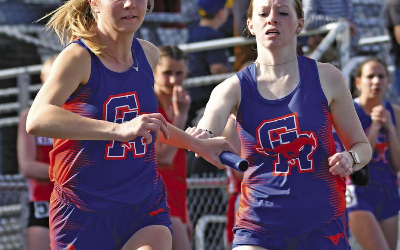 Photo by Melissa Grover Junior Rylie Barker hands off to teammate senior Natalie Popken during the 4x800 meter relay. The relay team would earn a second place medal in the event with a time of 11:09.05.