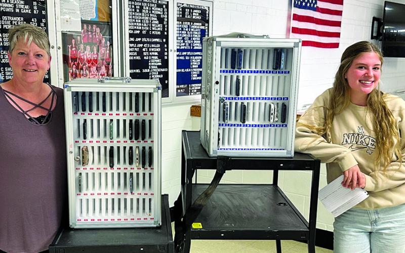 Photo by Scott Bidroski Mrs. Kacy Heiser (left) and GRHS junior Amara Funk (right) show off the new cell phone lockers at Gordon-Rushville High School. A new policy has been implemented to help limit distractions for the students during the school day.