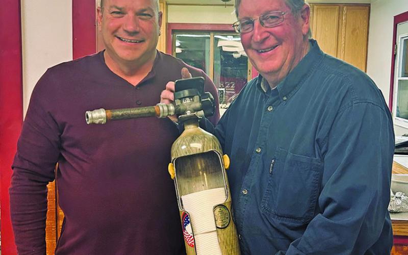 Courtesy Photo Rushville Fire Chief Keith Wellnitz (left) presents an interesting way to store your toilet paper to Jerry Kearns (right) in recognition of his 35 years of service to the Fire Department.
