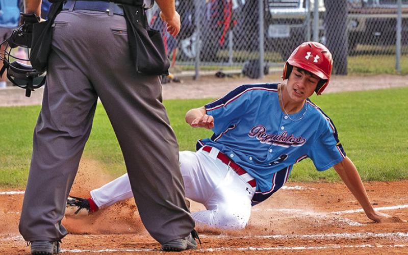 (Photo by Richae Malara) Freshman Joey Ziller slides into home safely for one of the 14 runs the Regulators scored in the win over Orchard Tri-County on Friday, July 11.