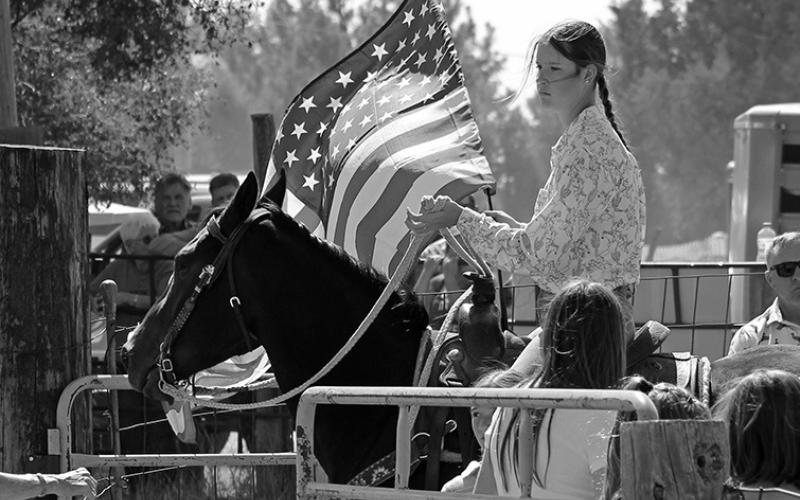 Photo by Heidi Beguin Kati Cox carries the flag for the singing of the National Anthem before the Fun Days Rodeo begins.