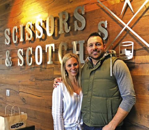 Courtesy Photo Tanner Wiles, along with his Director of Grooming Brandi Busboom, take a photo in front of the Scissors &amp; Scotch signage at his Lincoln location.