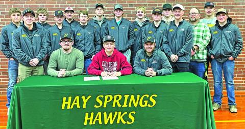 Photo by Jessica Minkten Hay Springs senior Gage Mintken (center) signs his National Letter of Intent with Chadron State College on Wednesday, February 7. Mintken was joined by his Hawks teammates and coaches, along with family and friends, for the event.