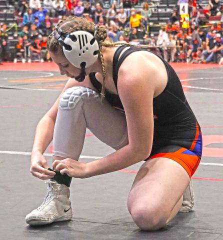 (Photo by Scott Bidroski) Senior Kirsten Heck puts on her green ankle band prior to her match on Saturday, January 24 in which she would win her 100th career match as a Mustang wrestler.