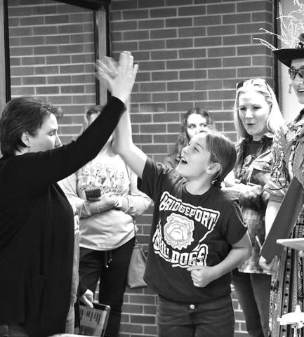 Photo by Chabella Guzman Completing her round with a high score, Brynn Little, center, of Bridgeport, gets a high-five from a fan.