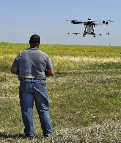 Photo by Heidi Beguin Southpaw Aerial Co., LLC’s Seth Tausan helps guide the spray drone as it comes in for a landing.