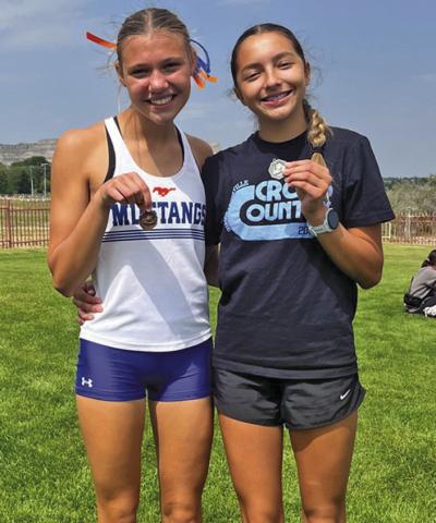 (Photo by Amy Schmidt) Brittney Dehning (left) and Rarity Cournoyer (right) show off the hardware from the Gering Cross Country meet on Friday, September 5. Dehning finished 6th and Cournoyer placed 2nd for the Mustangs.