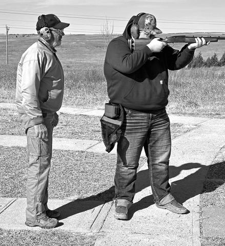 Photo by Rodney Beguin Junior Niobrara Trapshooting Coach Buster Kearns instructs 4th year team member Ethan Bourne at the shooting range.