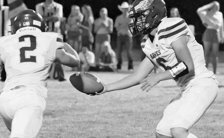 Photo by Harry Lipsiea, Keith County News Junior quarterback Jaydub Turman hands the ball off to senior Tripp Buettner. Buettner would rush for 187 yards this week and three scores but the Hawks fell short to Wallace, 50-22.