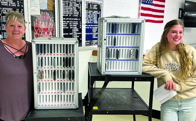 Photo by Scott Bidroski Mrs. Kacy Heiser (left) and GRHS junior Amara Funk (right) show off the new cell phone lockers at Gordon-Rushville High School. A new policy has been implemented to help limit distractions for the students during the school day.