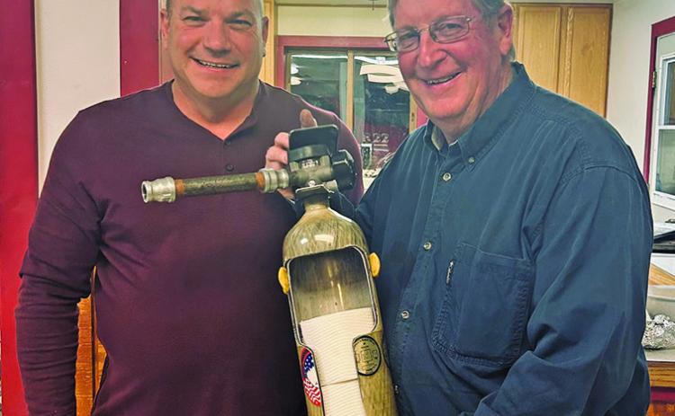 Courtesy Photo Rushville Fire Chief Keith Wellnitz (left) presents an interesting way to store your toilet paper to Jerry Kearns (right) in recognition of his 35 years of service to the Fire Department.